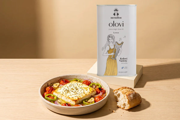 Baked feta recipe: golden Greek baked feta with tomatoes and peppers in a dish next to a Memilon Lesvos extra virgin olive oil tin