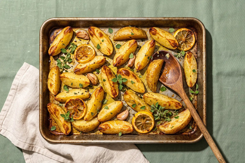 Greek lemon potatoes roasted with olive oil, garlic, oregano and lemon slices in a baking tray