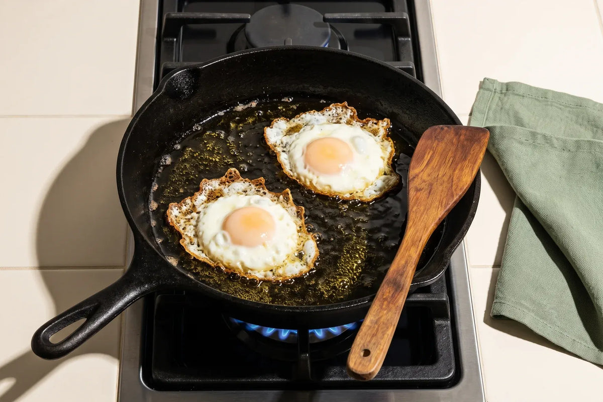 Eggs frying in extra virgin olive oil in a cast-iron skillet on a gas stove
