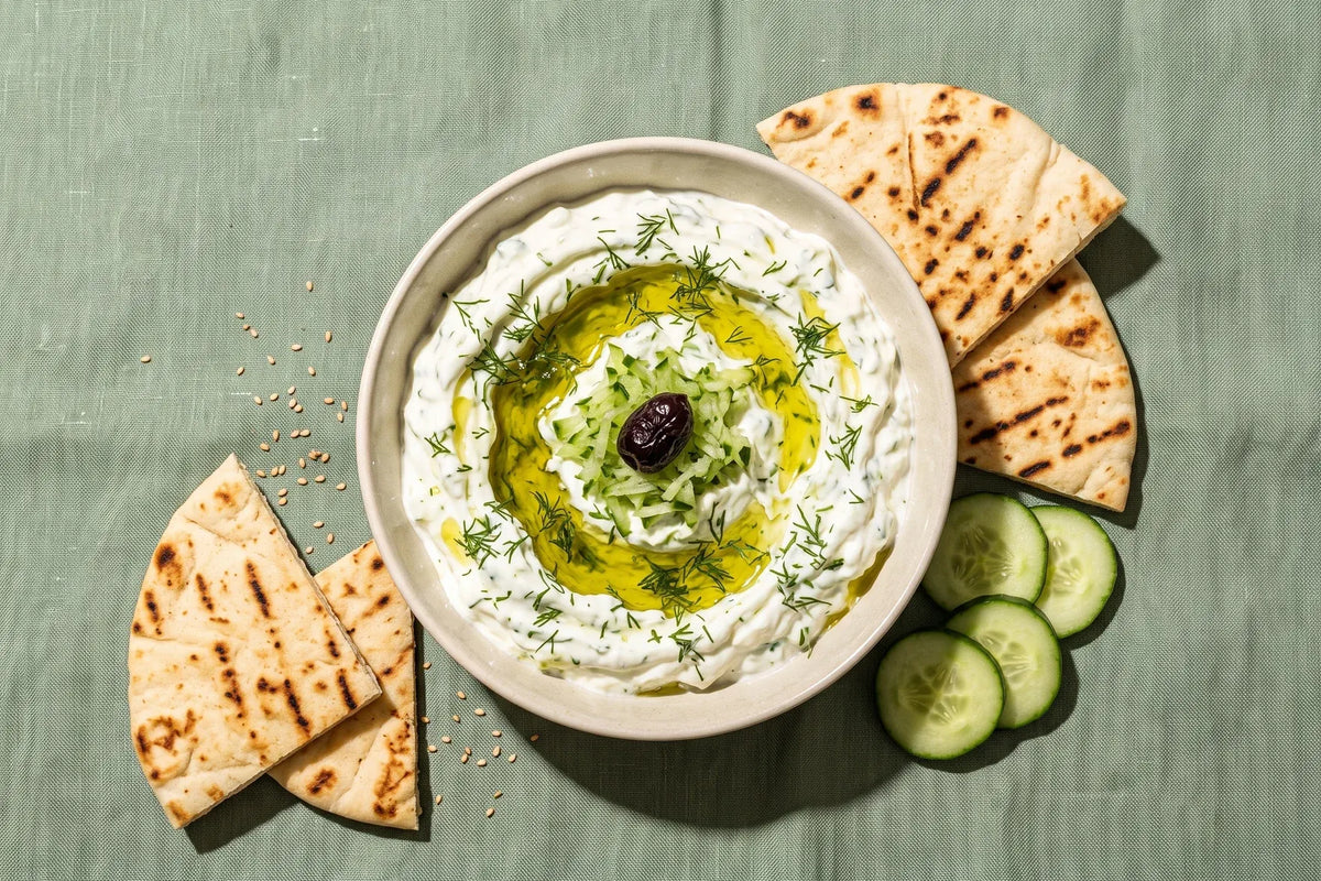 Homemade Greek tzatziki drizzled with olive oil with grilled pita and cucumber slices