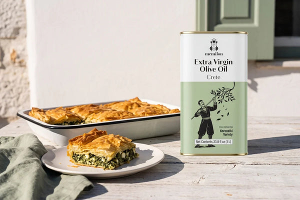 Spanakopita recipe: golden Greek spinach and feta phyllo pie on a sunlit table next to a Memilon Crete extra virgin olive oil tin
